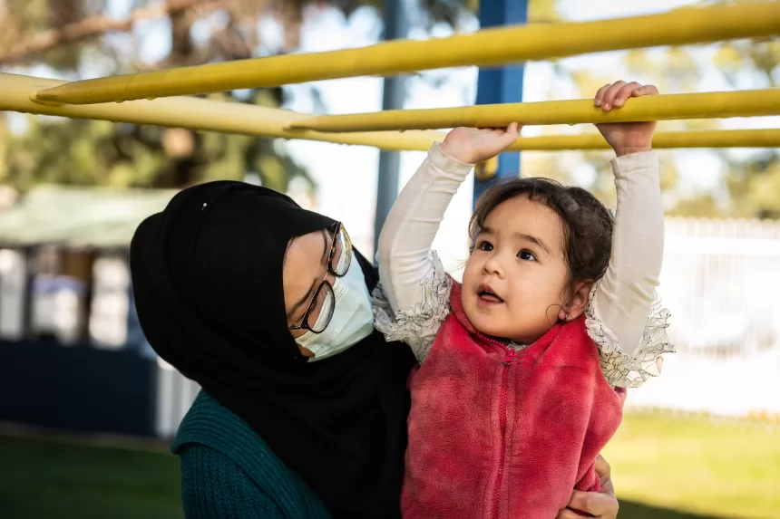 Mother helping child on monkey bars