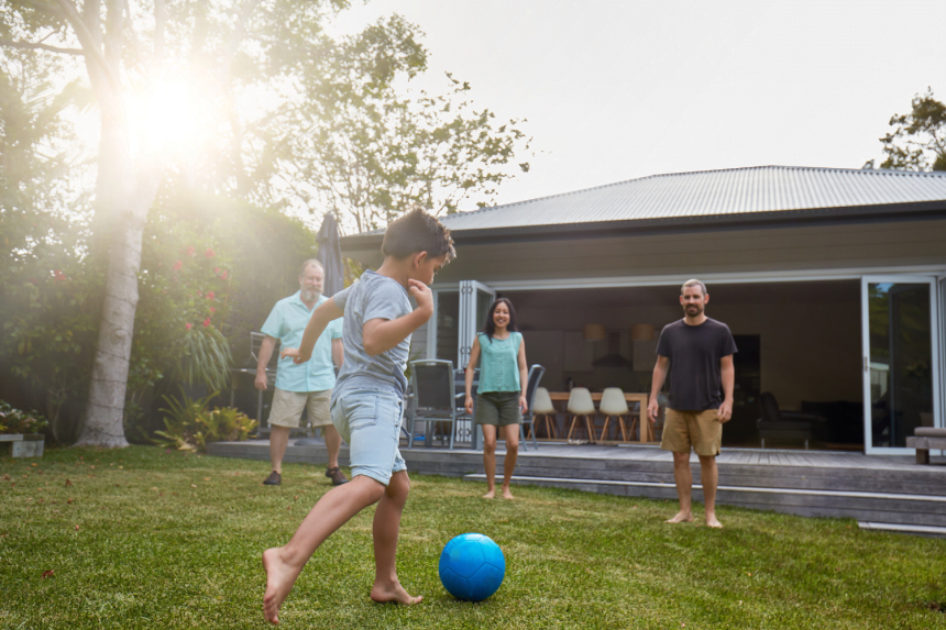 Child kicking ball to three adults